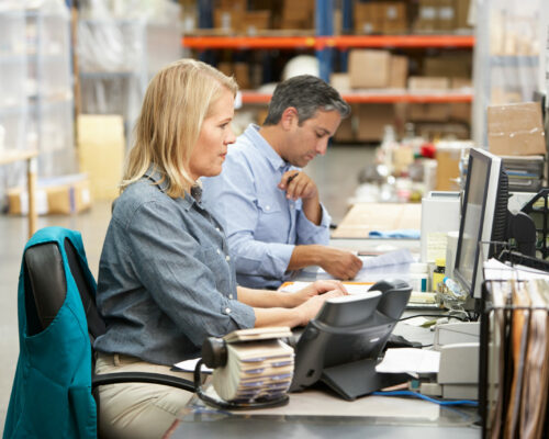 Business Colleagues Working At Desk In Warehouse